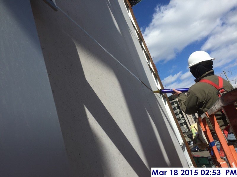 Continued caulking the stone panels at the South Elevation